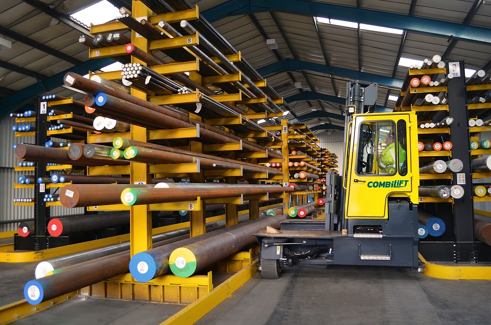 Worker operating a yellow Combi C-series, ready to lift steal pipes